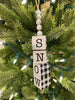  A Snow Cube Ornament with the letters of the word SNOW on each individual cube.The other three sides of the cube are painted in black and white plaid. The cubes are moveable so you can see the different sides. There is five white beads at the top of the cube stack hung on a jute rope hanger.