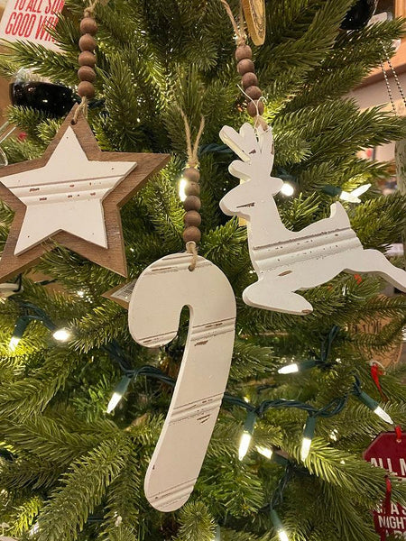 Three Chippy wood ornaments. There is a star, candy cane and a reindeer made of wood and painted and then the wood is distressed for the chipped paint look. The ornaments are white and at the top of each is natural coloured brown beads strung on a jute hanger.