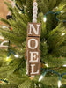 The Beaded Cube Ornament with the word Noel. The natural coloured cubes are printed with a single letter on all four sides and are moveable. Five White beads are at the top and one at the bottom of the ornament. 