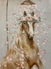  This blue toned background print of a brown horse being showered with pink and white petals in a white vintage claw foot tub is framed with a brown distressed wood frame. This is close up of the horse and its flowing mane and the white and pink petals.