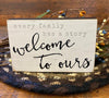 The Family Mini block sign that says: Every family has a story - welcome to ours. The edges are black and the writing is gray and black. 