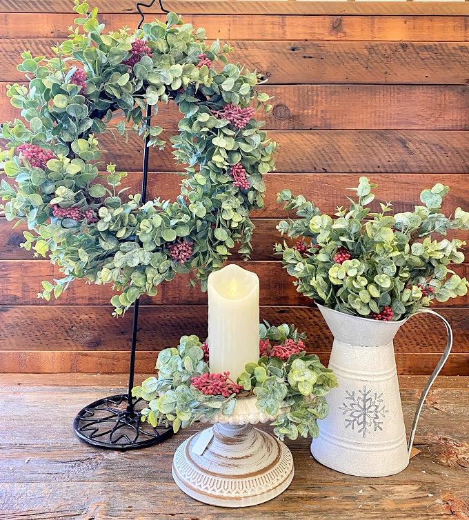 Wreath, candle ring and sprays that are a part of the Holiday Eucalyptus collection. All of the pieces are white dusted eucalyptus with red berries incorporated in them as well. 