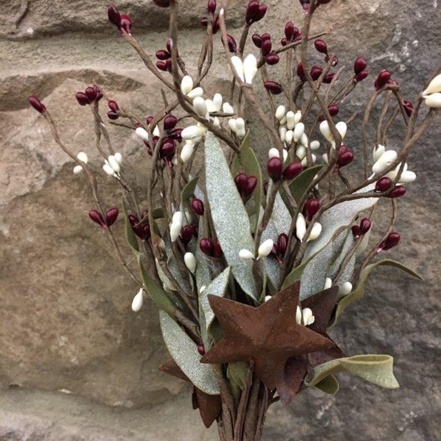 A close up of a  12" berry pick with red and white coloured mini oblong shaped berries with mini rusty stars.  This pick also has oblong shaped green leaves. This berry pick is perfect for your country and farmhouse decor.