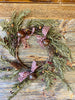 The Rustic Winter wreath and pick feature red and tan gingham, rusty bells and red and mustard colored berries mixed in with a dark green.  Shown here is the candle ring/wreath.