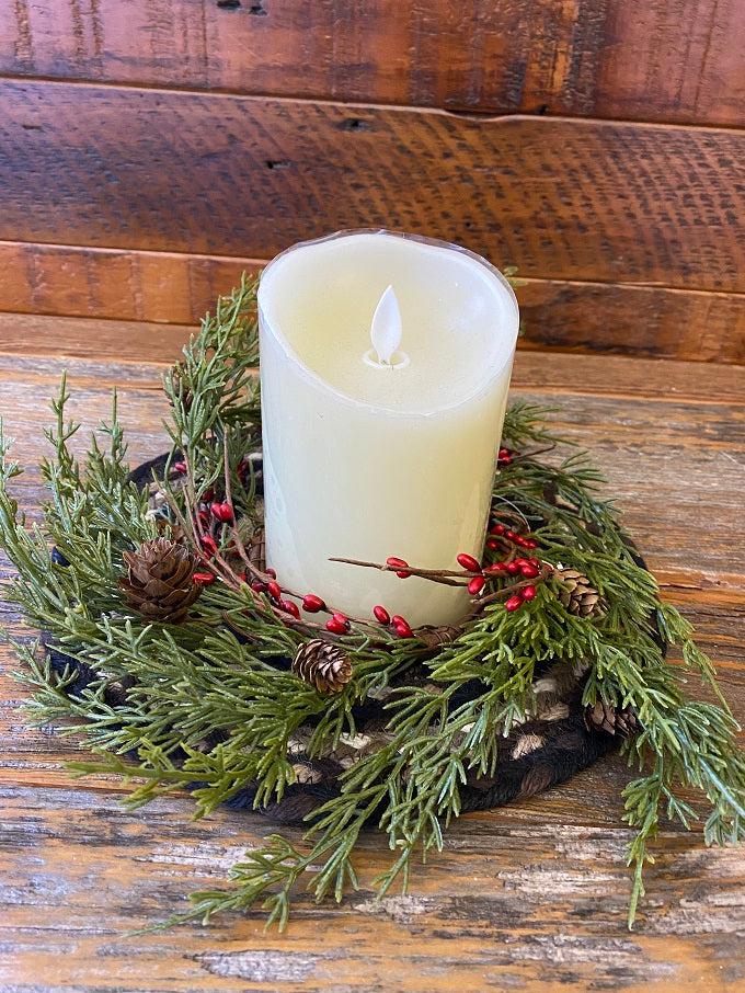 The evergreen pine wreath features green pine like stems, and red berry pips and pine cones.  It is shown here with a LED candle.