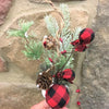 A pick made up of snowy Christmas greens, and round red and black check fabric coloured balls, pine cones and jute rope.