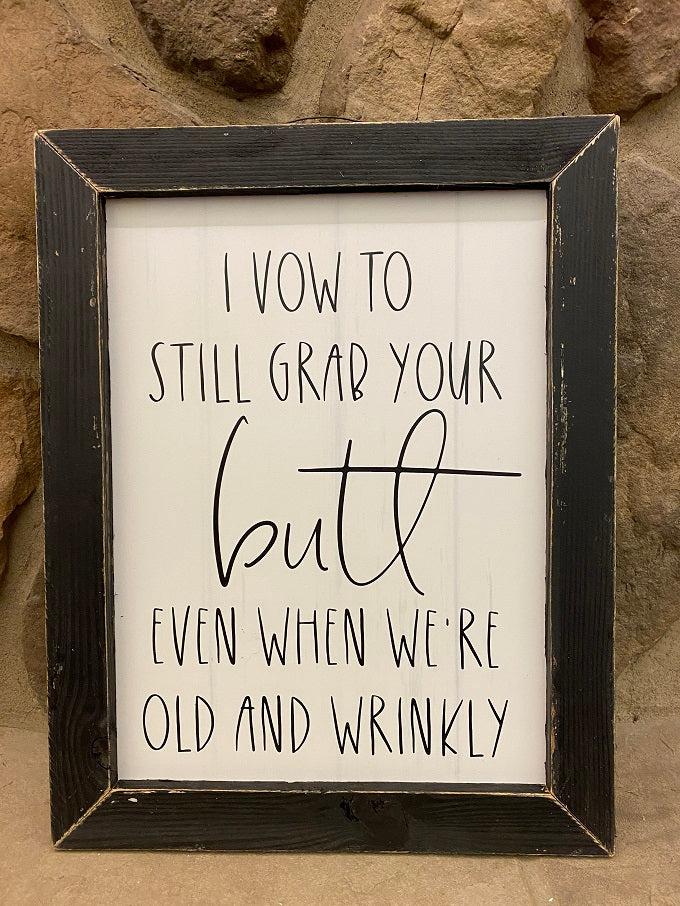 This is a picture that says: I vow to still grab your butt even when we are old and wrinkly is printed in black on a white background. It is framed in a black distressed frame. 