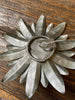 The back of the metal flower showing the hook. It is a hook that would need a nail to hang it. 