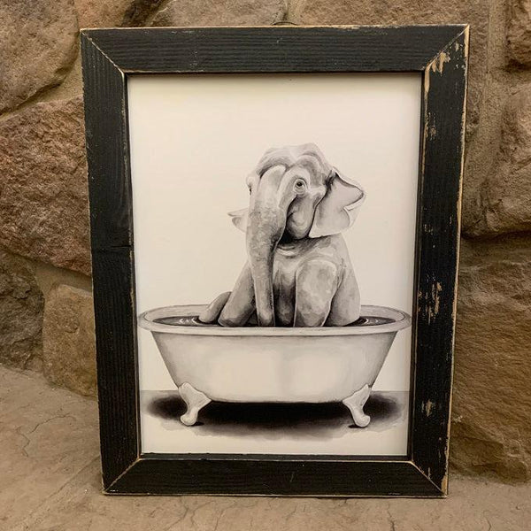 This cute picture has an gray elephant taking a bubble bath and would be adorable in a kids bathroom. It is framed with a black distressed wood frame that is 1" wide.   The frame has a vintage wire along the top of the frame for quick and easy wall hanging.
