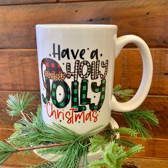 This is a white ceramic mug that says in a colour font on both sides: Have a Holy Jolly Christmas.