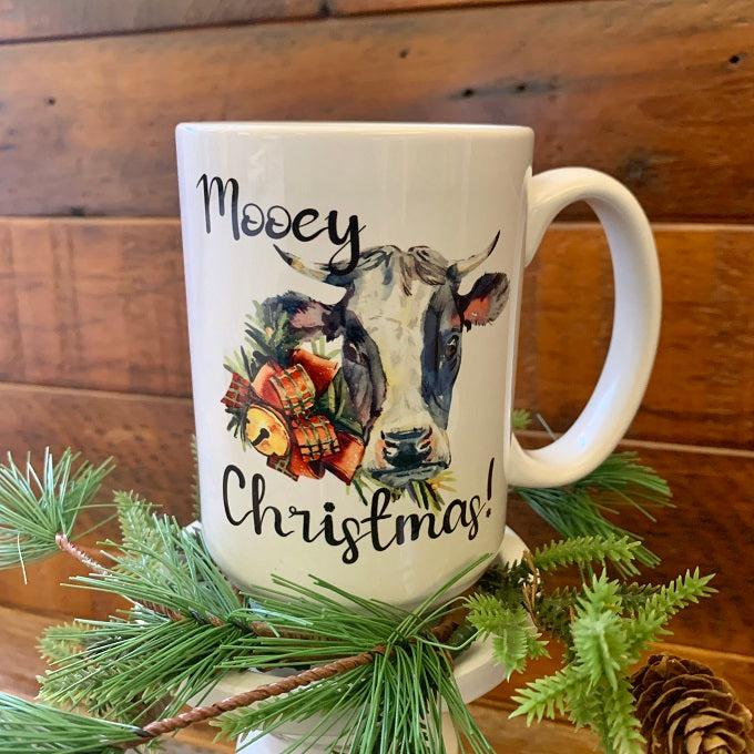 A white ceramic mug printed on both sides with the saying Mooey Christmas