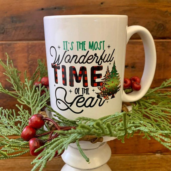 It's the Most Wonderful time of the year mug is printed on both sides. The lettering is green and black and the word time is printed in red and black buffalo plaid.