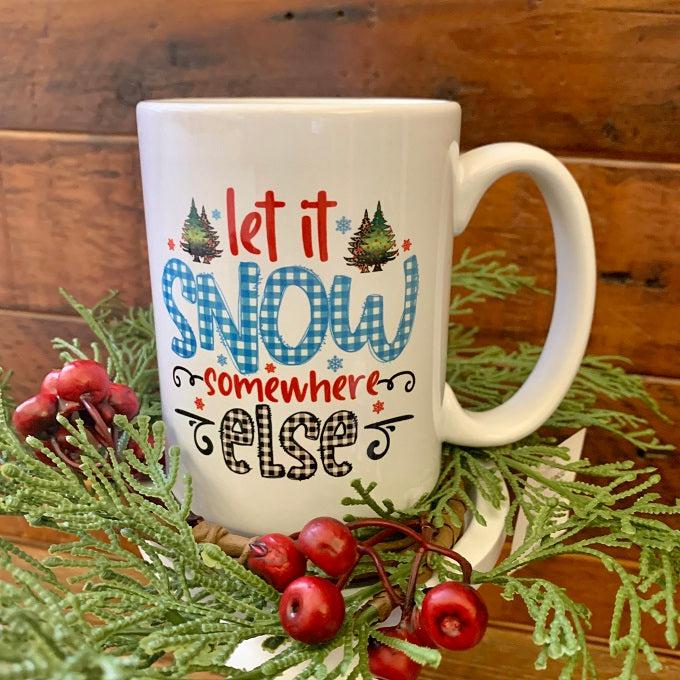 Let is Snow Somewhere Else is printed on both sides of a white ceramic mug. Different colours of fonts have been used. 