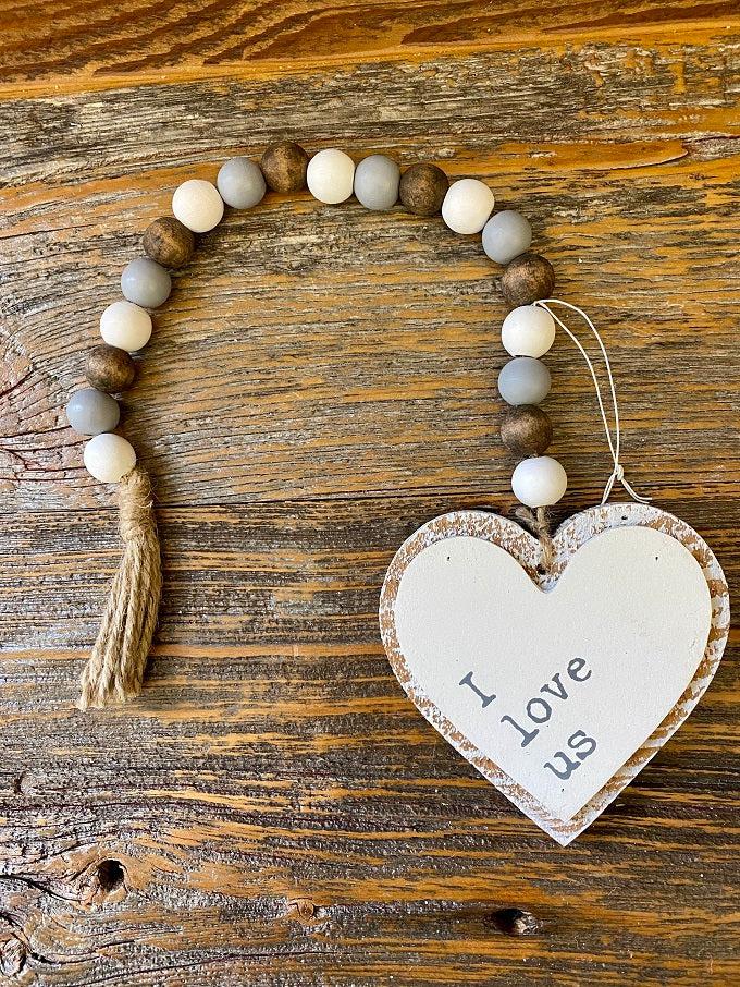 The I Love Us Beaded Garland is a wooden heart at the bottom of a multi-coloured beaded rope. In white, natural and gray tones this simple farmhouse garland will go anywhere with anything. 