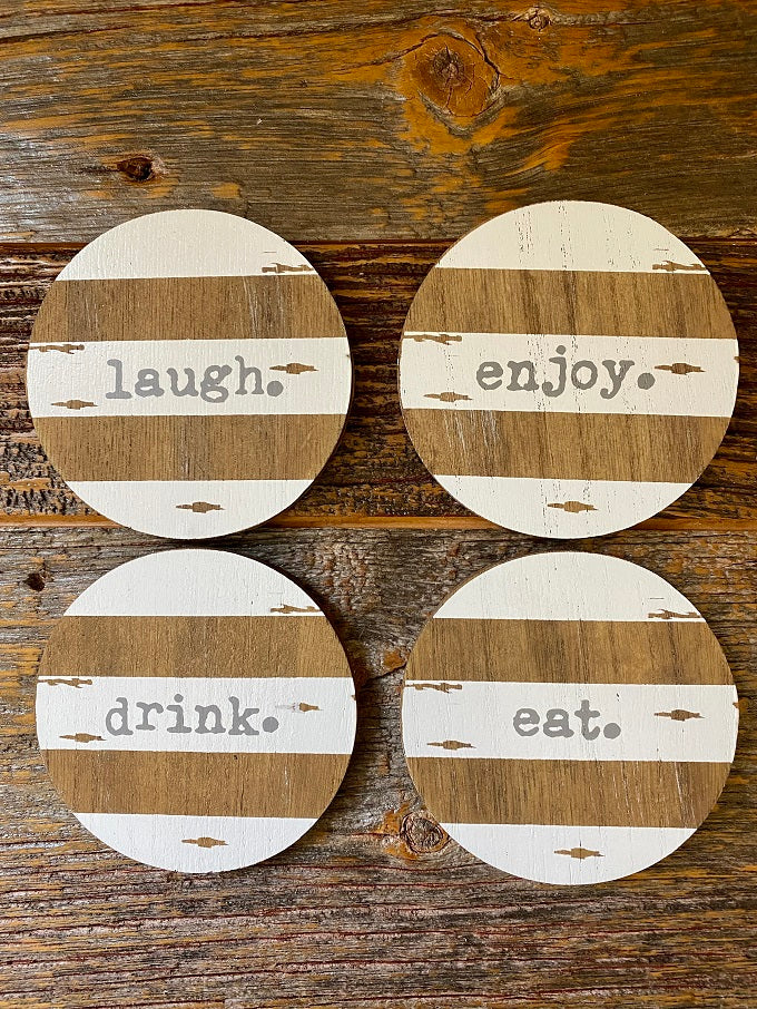 Four chippy paint wood coasters, painted with white distressed stripes. Each has a different word - laugh, enjoy, drink and eat. 