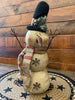 The Cranberrry plaid scarf snowman is a three stack snowman and has a black hat with cranberry and tan plaid trim and matching scarf. There  is a jingle bell trim on his hat and one metal snowlake on his middle and bottom stack. He has two twiggy arms. 