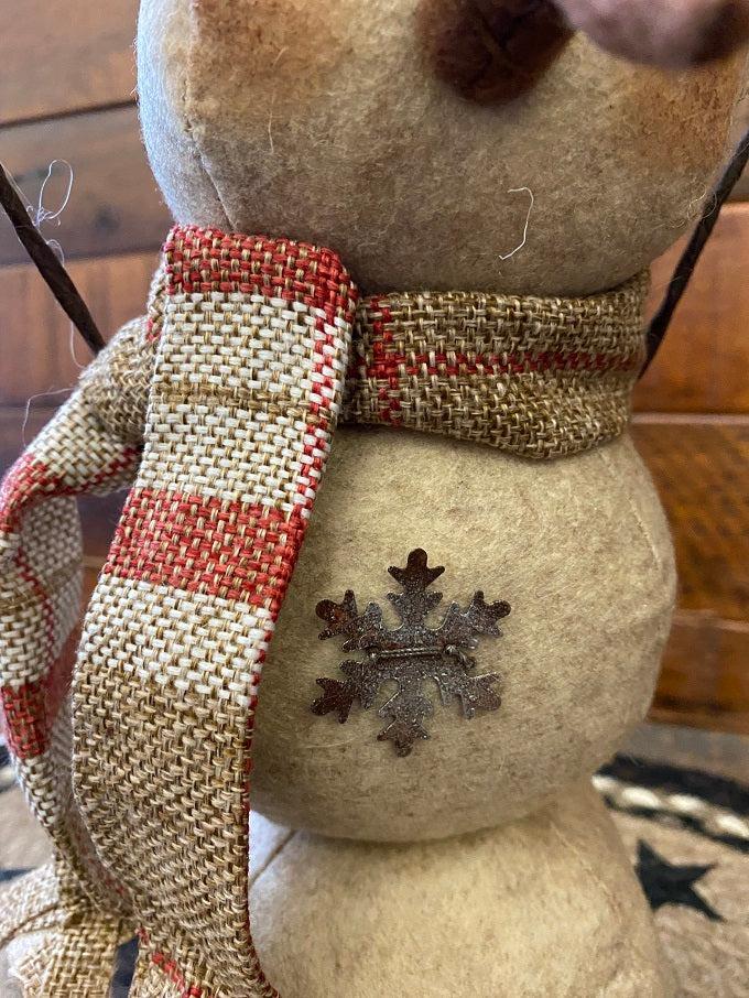 The Cranberrry plaid scarf snowman is a three stack snowman and has a black hat with cranberry and tan plaid trim and matching scarf. There  is a jingle bell trim on his hat and one metal snowlake on his middle and bottom stack. He has two twiggy arms. 