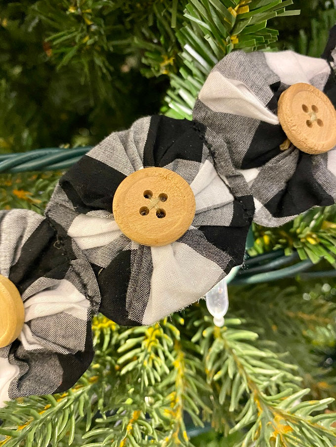 The fabric Yoyo garland is a pretty farmhouse garland. Black and white fabric circles are drawn together to look like flowers and a button is sewn onto each flower of this 6 foot long garland.