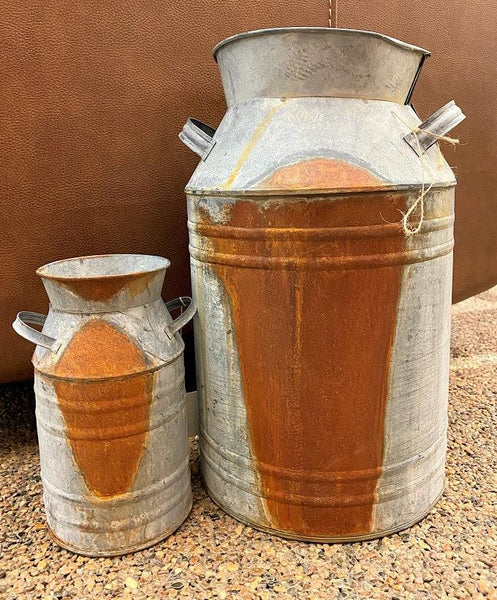 Two galvanized milk cans in two sizes large and small are shown. Both have a spot of rust on them. 