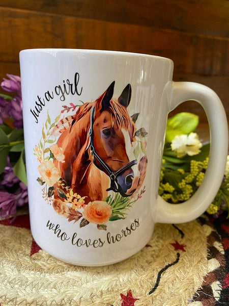 a white ceramic coffee mug that is imprinted on both sides with a pretty picture of a brown horse, with a white nose and black bridle surrounded by a ring of flowers,. The words "just a girl who loves horses" is written in a pretty script around the horse image.