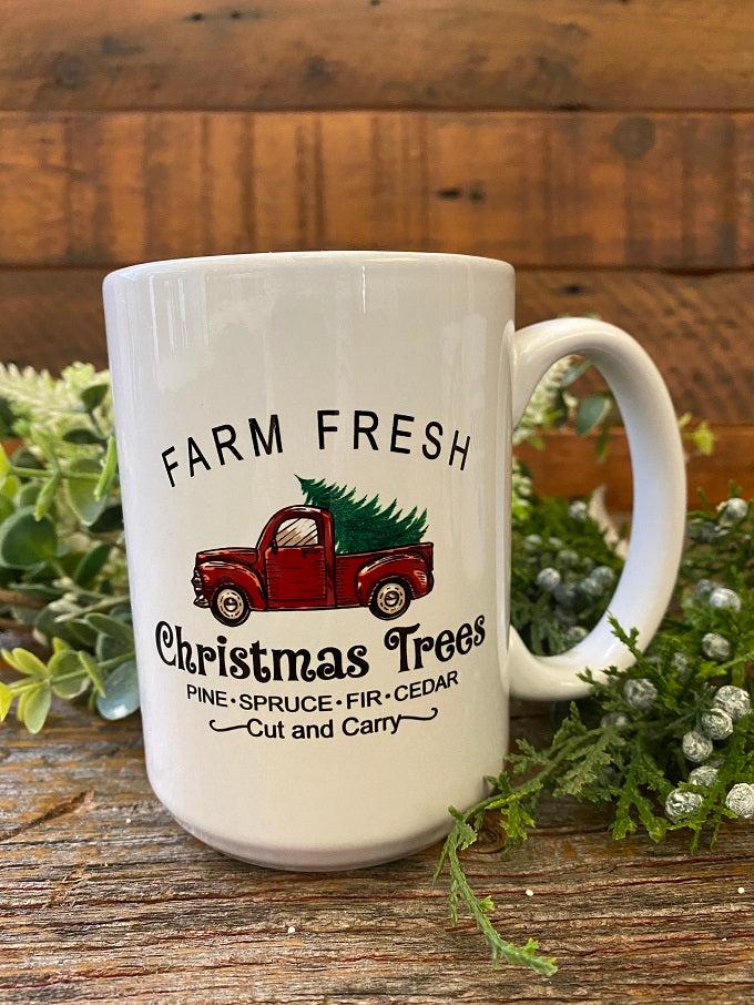 A white ceramic mug with a vintage red truck with a green tree in the back. It says Farm Fresh Christmas Trees on it.