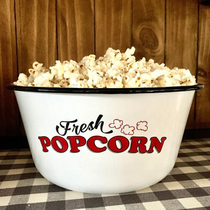 A white enamel bowl with a painted black rim has the words Fresh Popcorn on the side. 