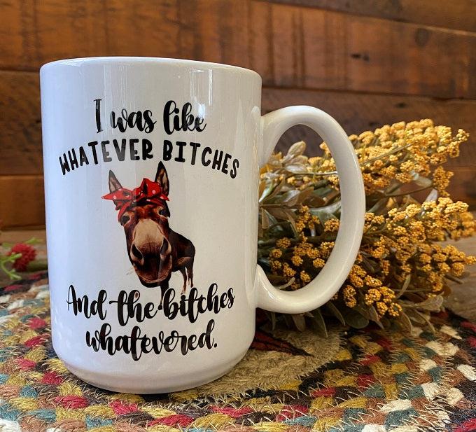 A white mug with a picture of a brown donkey with a close up of its face with a red bow and the saying in black writing "I was like whatever bitches and the the bitches whatevered.