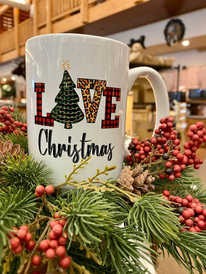 This is a white ceramic mug with LOVE in a bold font and the O is a Christmas tree. the mug says LOVE Christmas.